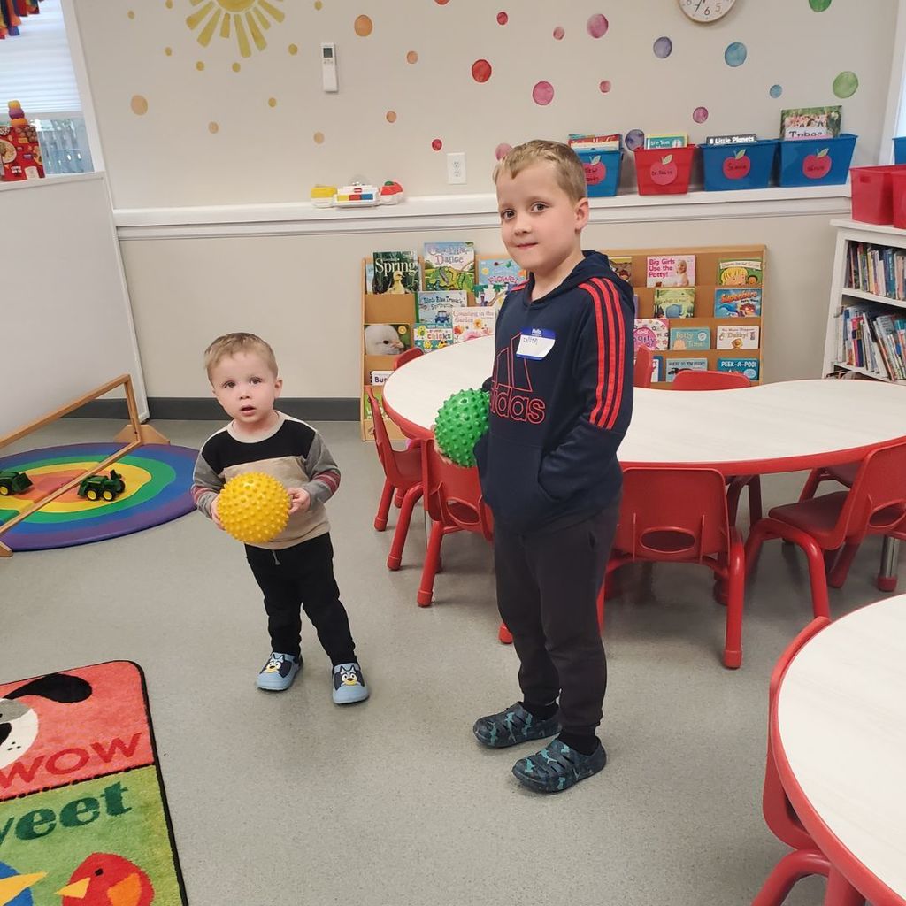 Two young boys holding small balls with soft spikes in a playroom