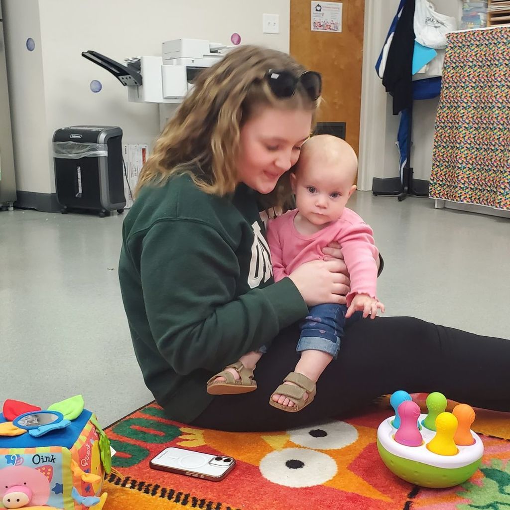 A high school student with a baby on her lap