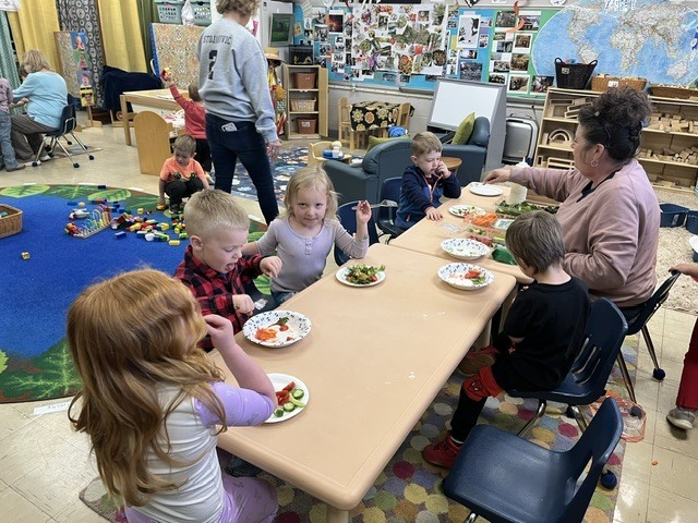 Picture of prekindergarten students eating their vegetables just like plant-eating dinosaurs