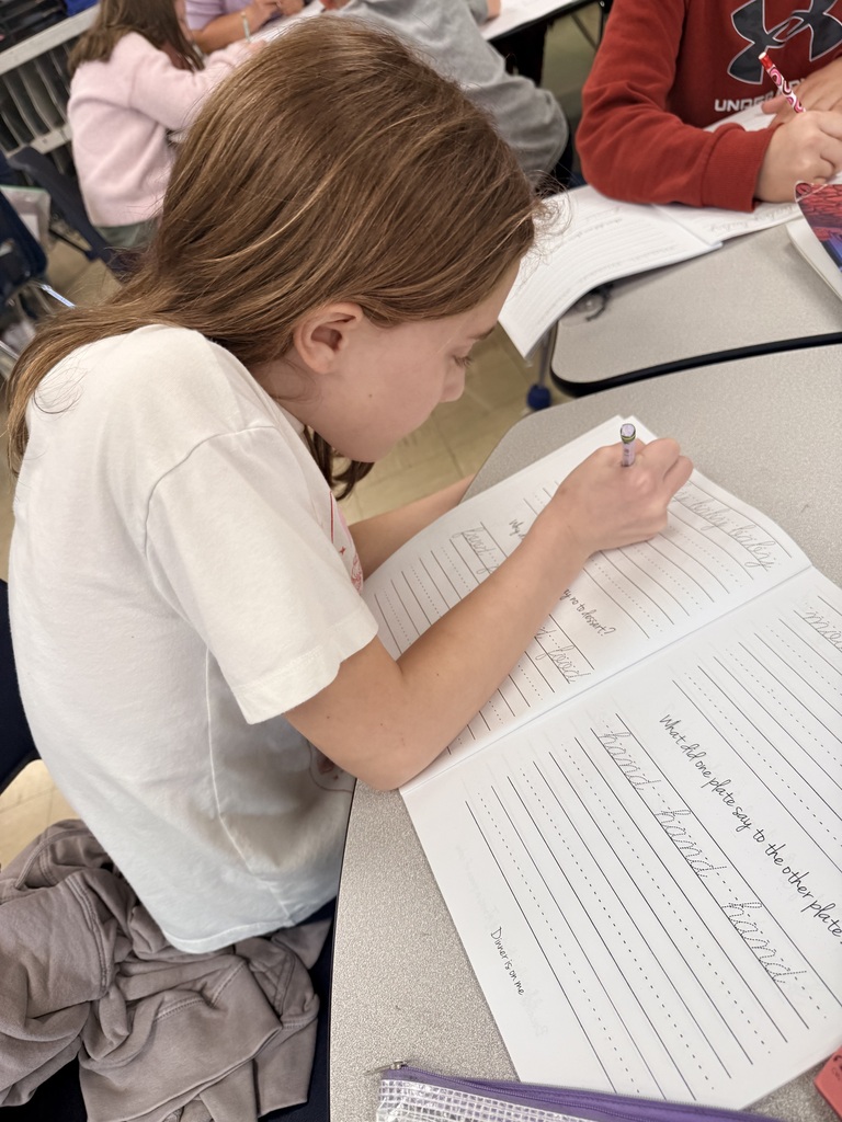 Photo showing a third grade student and the worksheets she is practicing cursive on