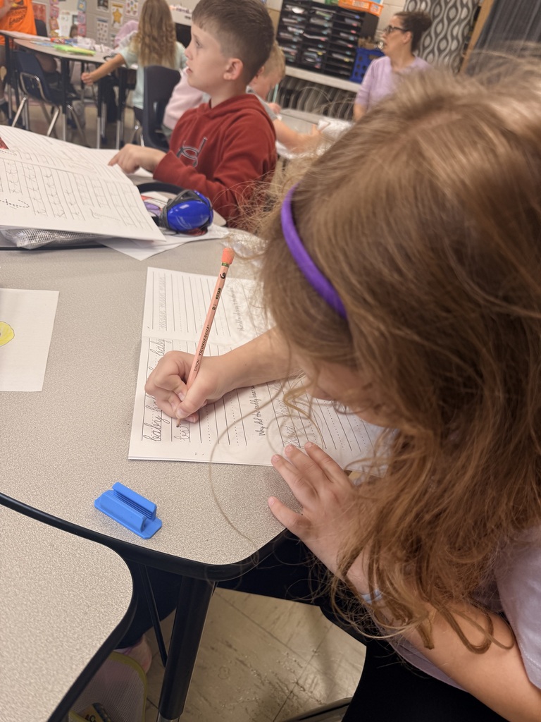 Photo showing two third grade students and the worksheets they are practicing cursive on