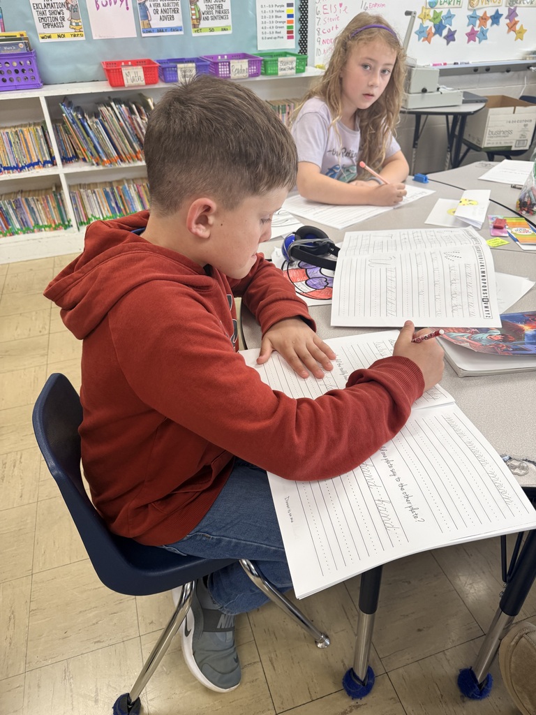 Photo showing two third grade students and the worksheets they are practicing cursive on
