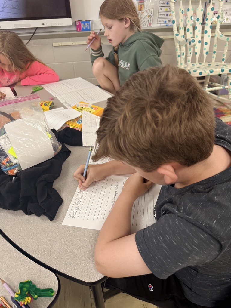 Photo showing three third grade students and the worksheets they are practicing cursive on
