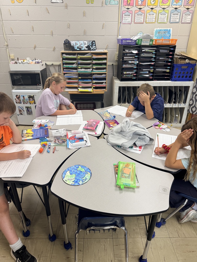 Photo showing four third grade students and the worksheets they are practicing cursive on