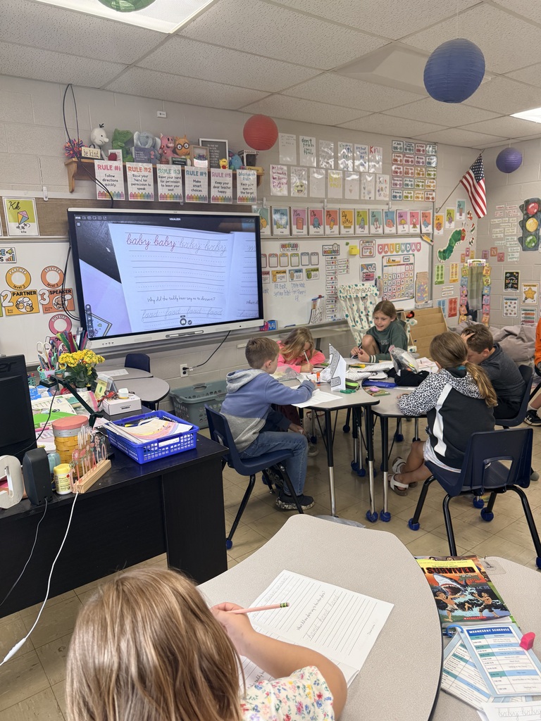 Photo showing six third grade students and the worksheets they are practicing cursive on
