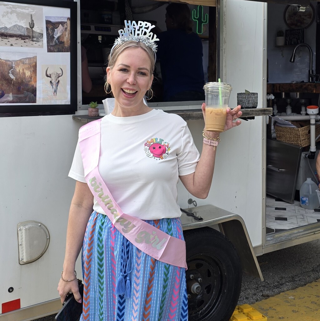 Photo of Ms. Jones with a "happy birthday" crown and sash and a drink from Stagecoach Coffee