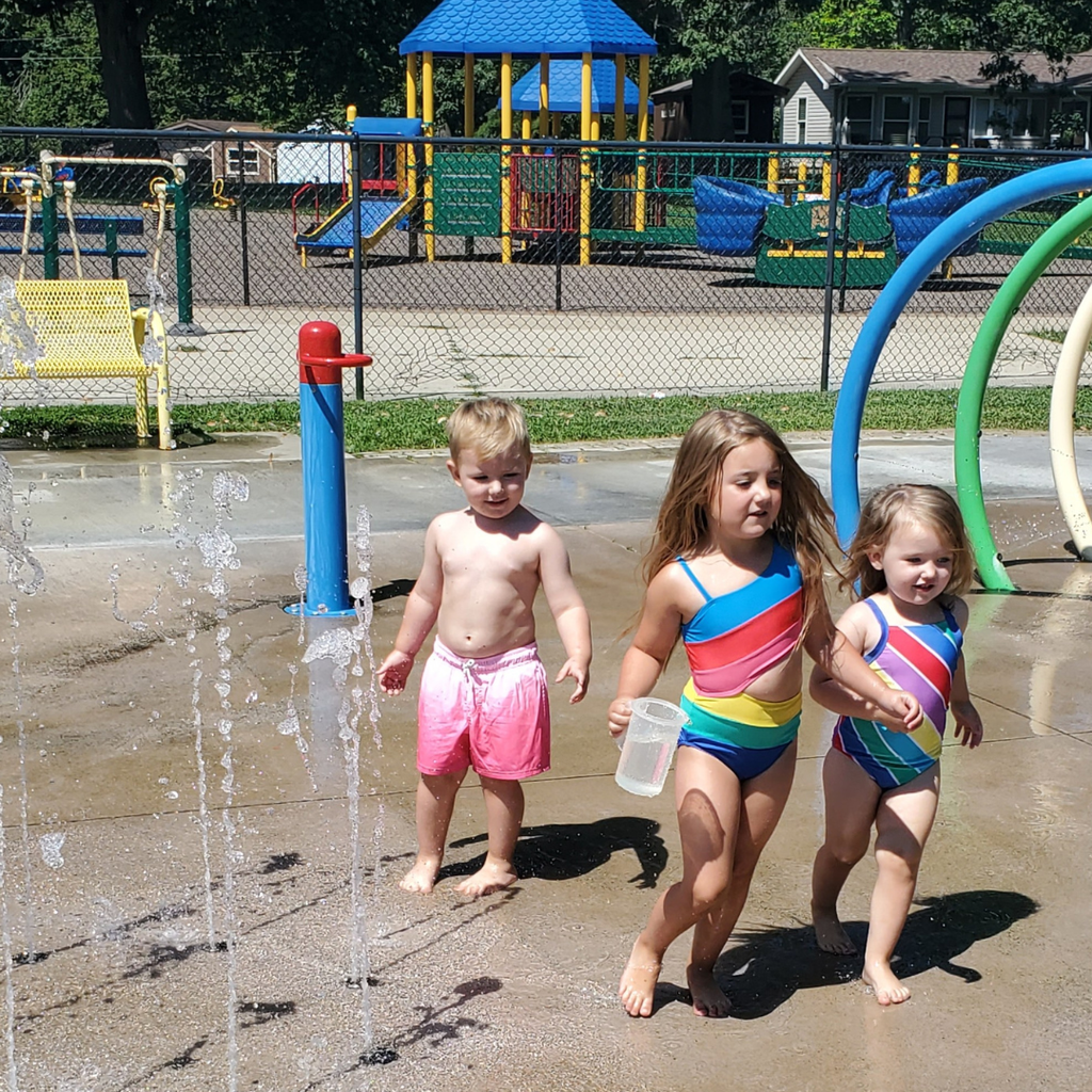 3 toddlers playing in water at splash pad