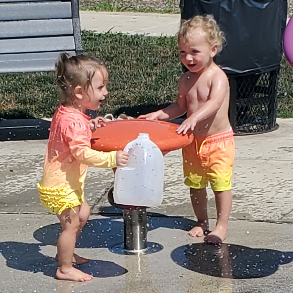 2 toddlers playing in water at splash pad