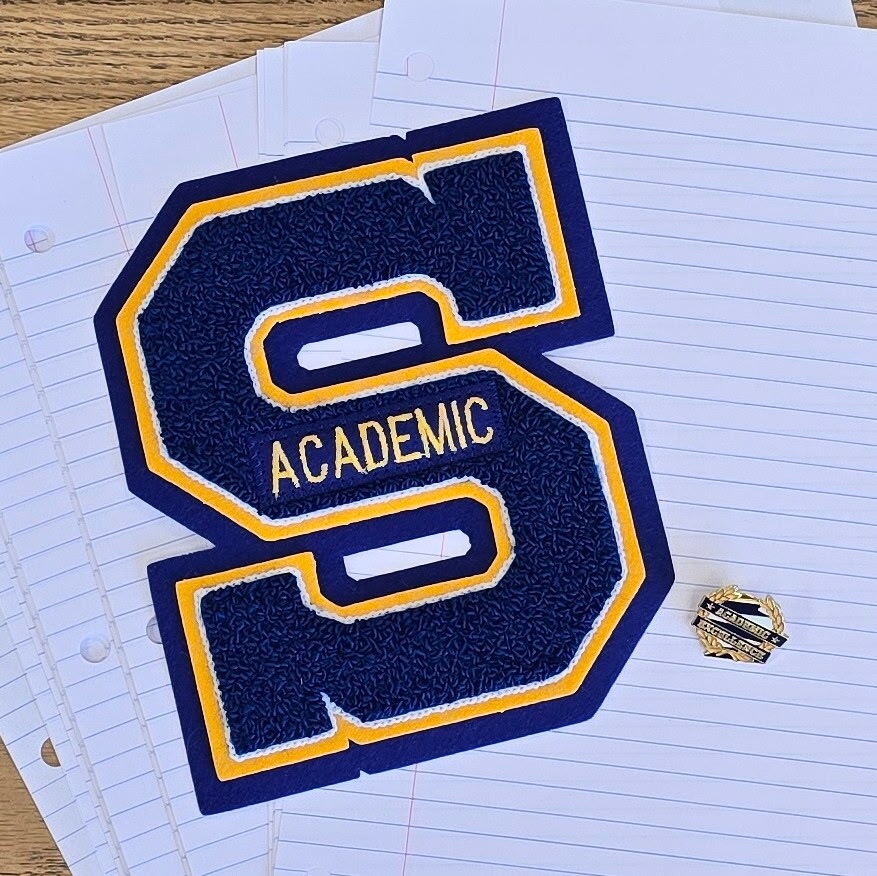 Image of a blue "S" with yellow trim emblazoned with the word "Academic" given to students to honor academic excellence