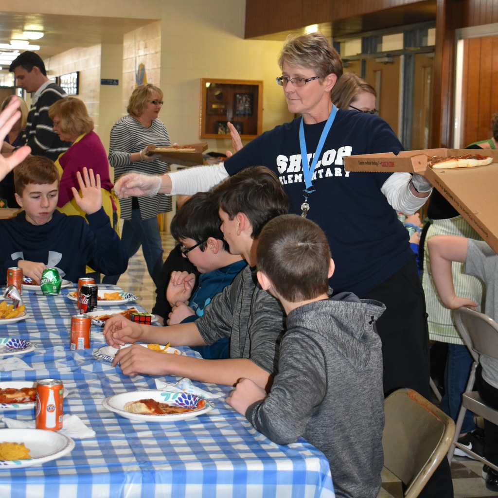 Ms. Sisk serving pizza on a junior high reward day
