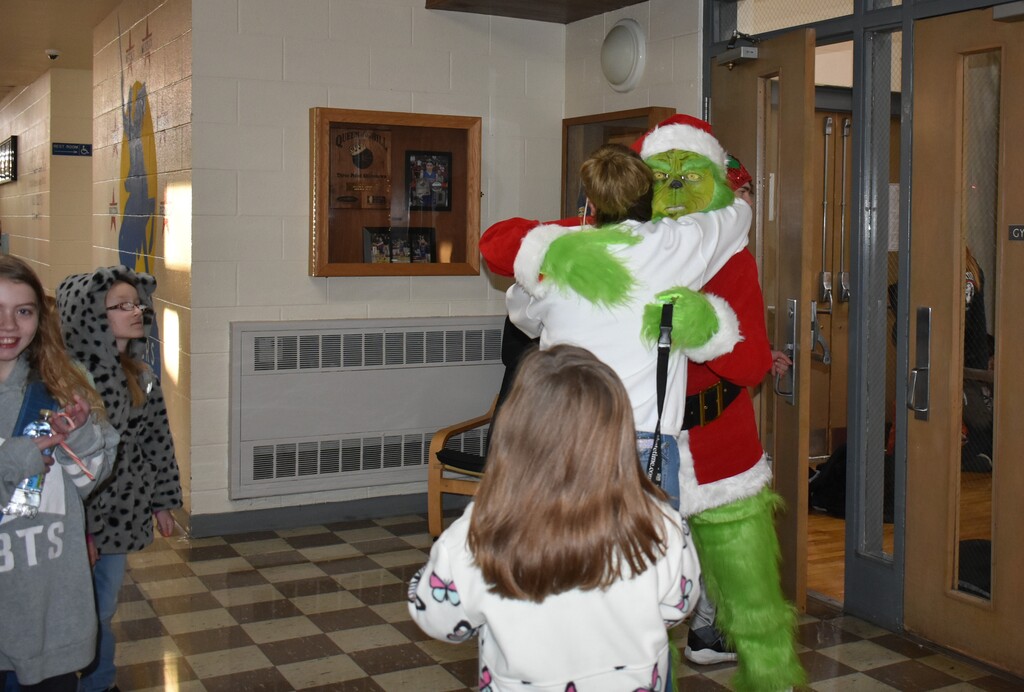 Ms. Sisk dressed as the Grinch and getting a hug from a student