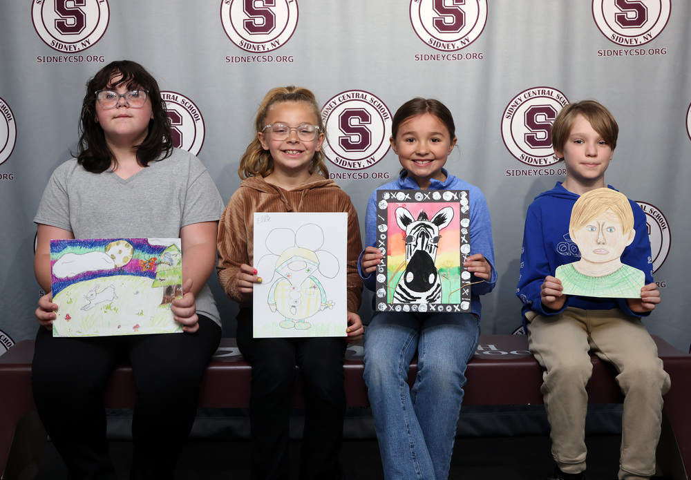 four students showing off their artwork