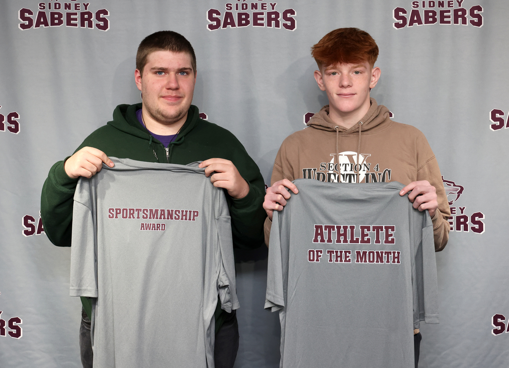 Nathan Strauss and Owen Mott holding up their t-shirts