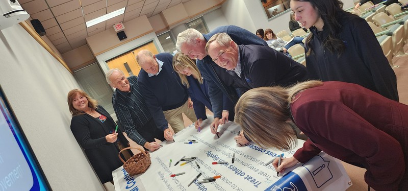 Board, Superintendent, and Deputy Superintendent sign Social Contract banner
