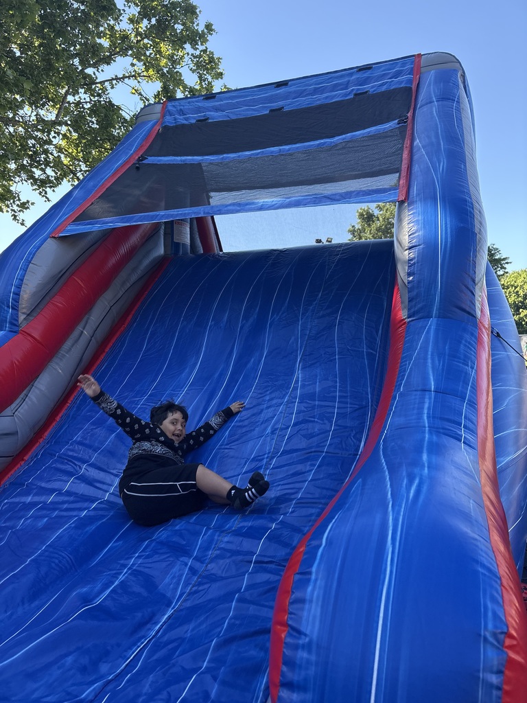 student sliding down bounce house slide
