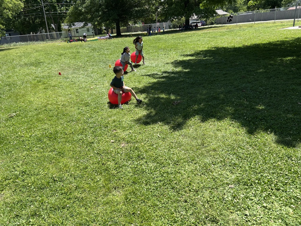 students bouncing on red balls during a relay race