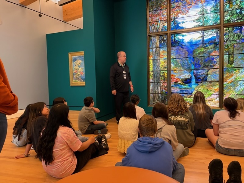 a Crystal Bridges instructor talking to students about a stained glass art piece