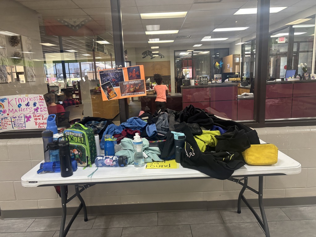 A white table with a bag, water bottles, and other items. A window in the background.