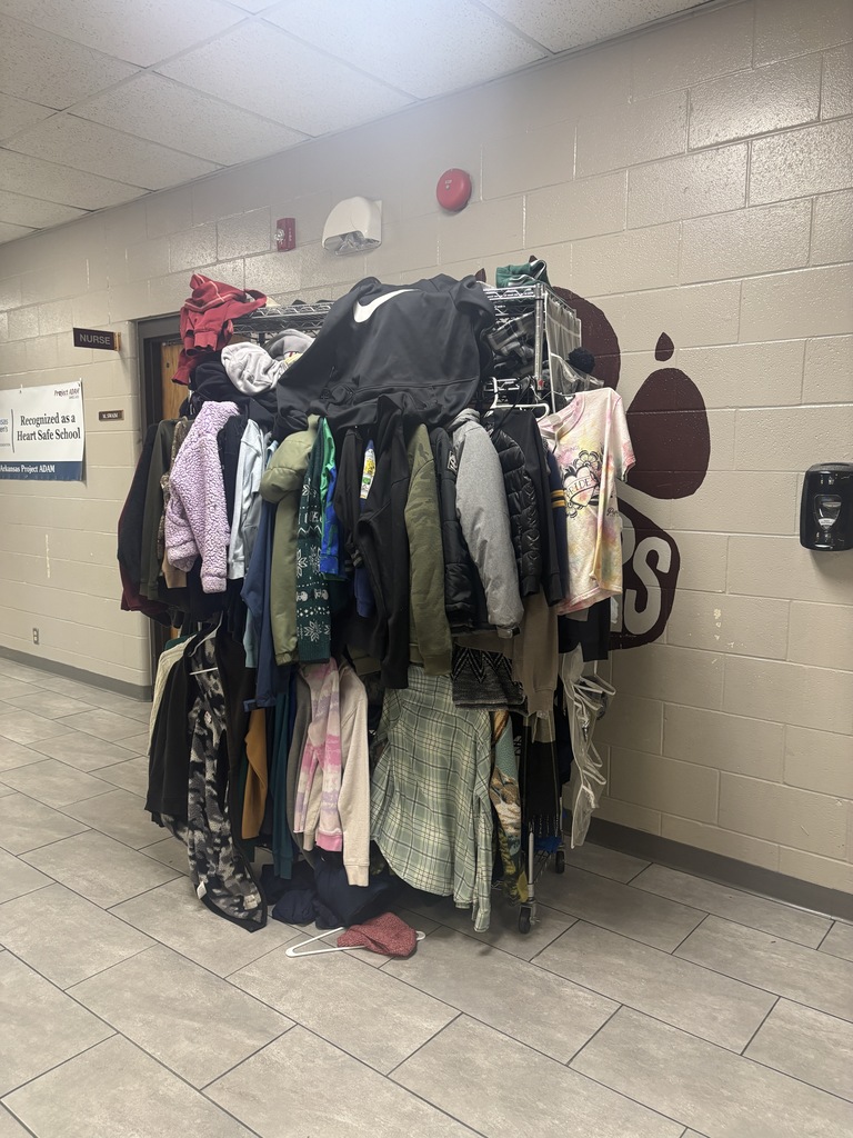 Clothing rack with various items including jackets and shirts in a hallway with a tiled floor.