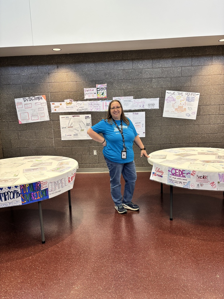 A history teacher showing off the art created by students in her history class. 