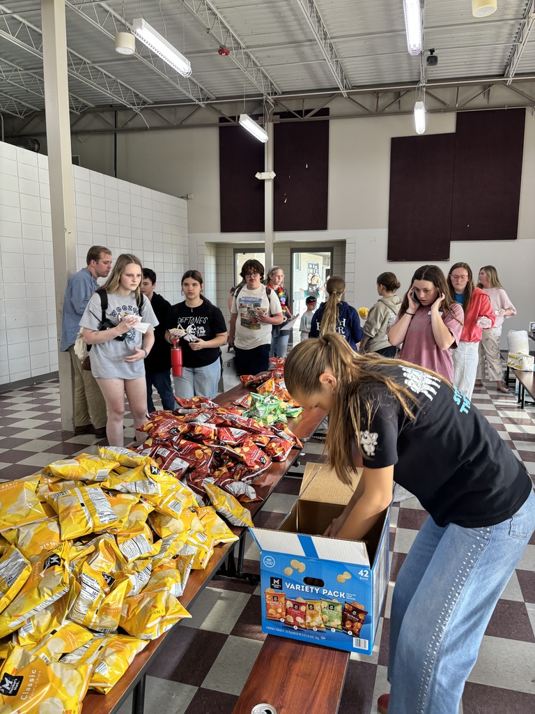 Group of students setting up to serve chips and hot dogs to families attending Steam night. 