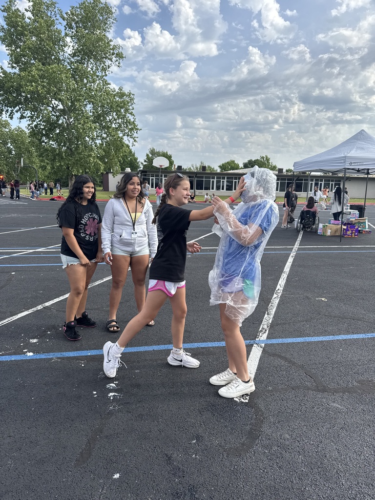 A student pieing another student in the face with whipped cream.