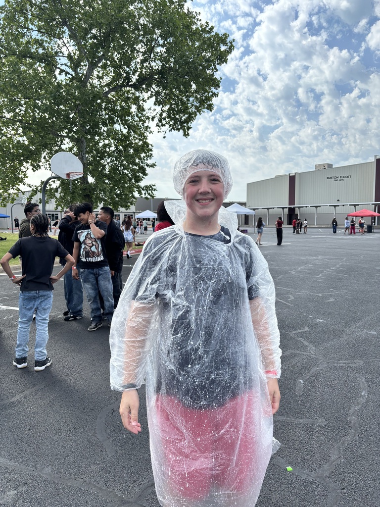 A student smiling after getting pied in the face and then running through the water.