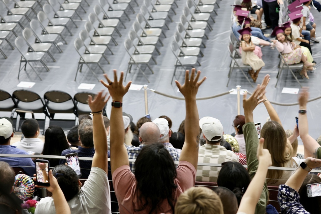 people in bleachers waving at graduates