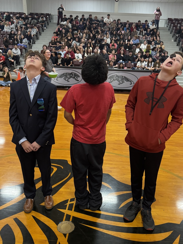 Three students trying to eat an oreo without using their hands. 
