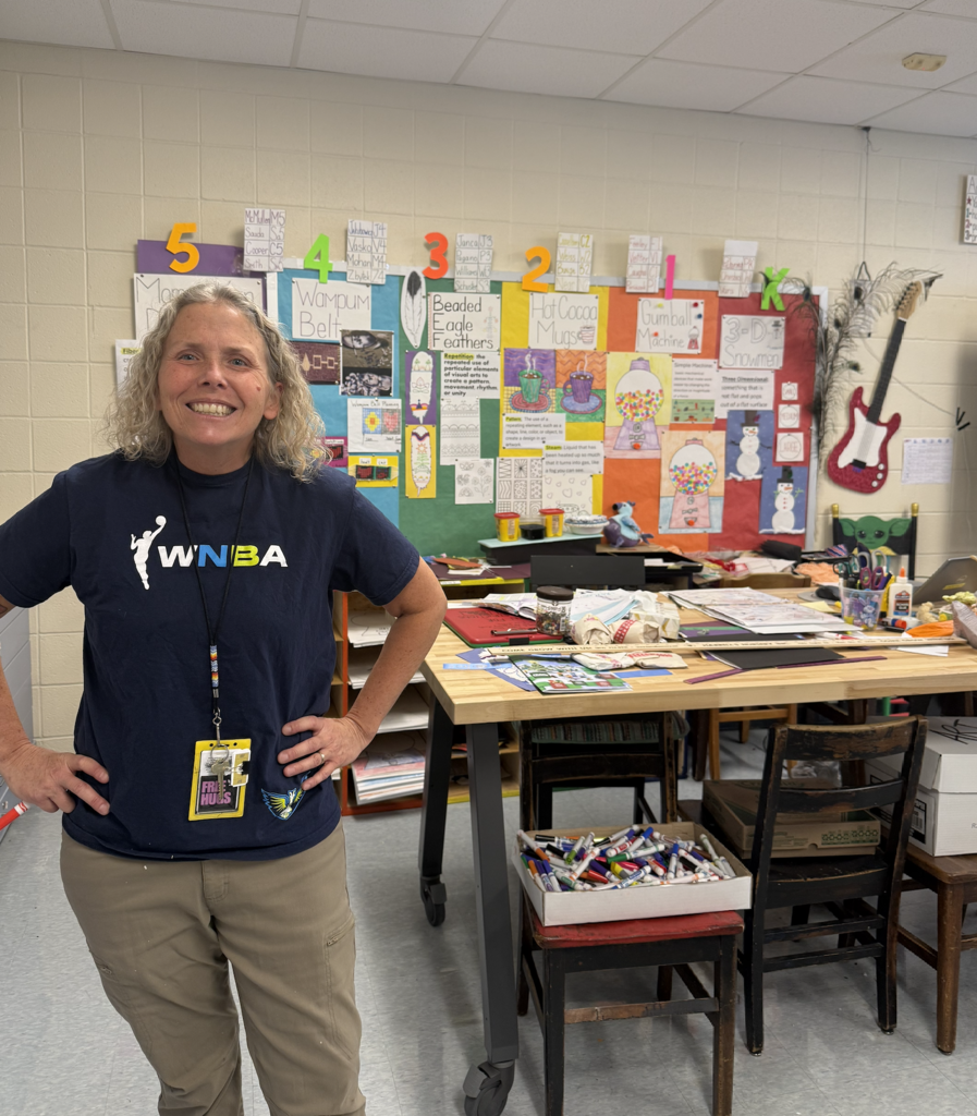 Mrs. ANderson in front of art bulletin board