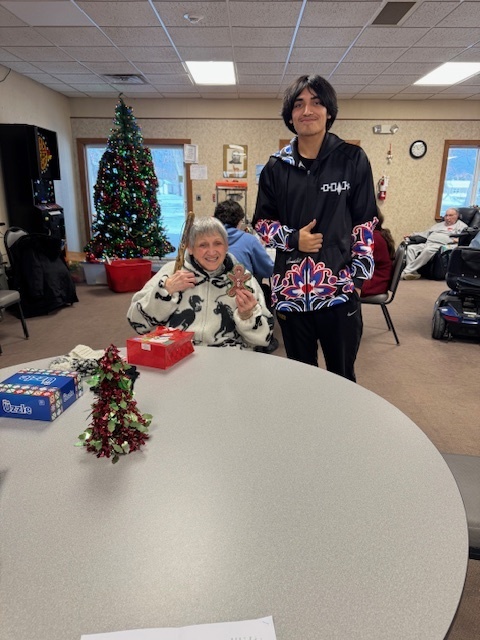 A student gives an ornament to an elder.