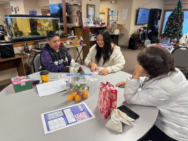 Student plays cards with two elders.