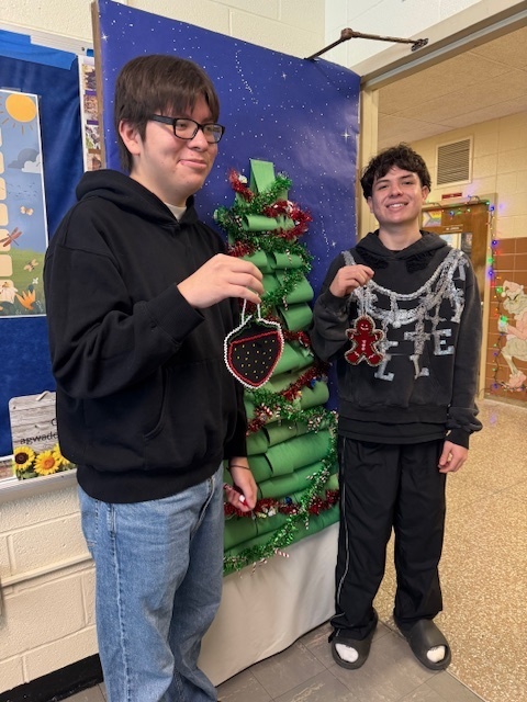 Two students hold ornaments.