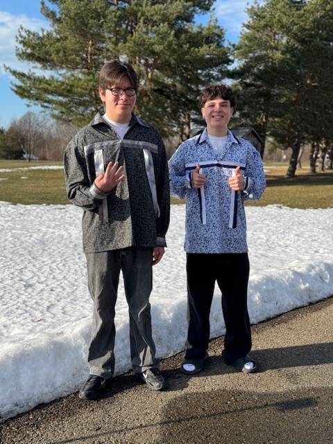 Two male students wear  the ribbon shirts that they made. 