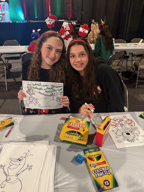 Two students help with coloring a winter scene. 