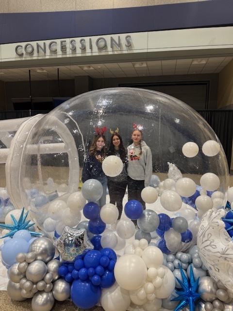 Three female students pose in a blowup igloo.