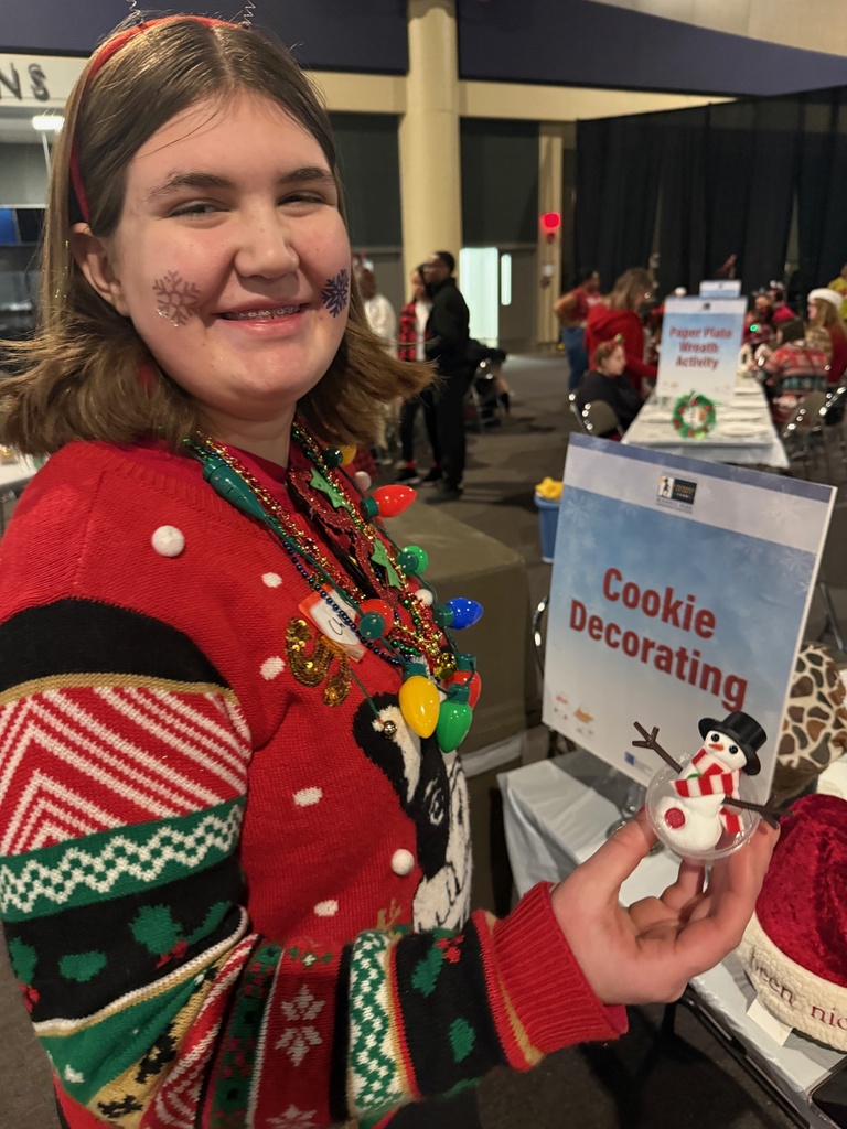 A female student holds up a marshmallow snowman.