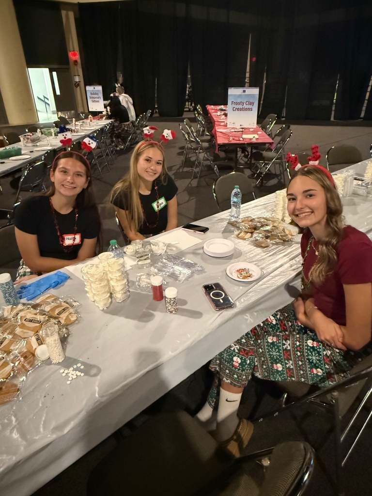 Three female students assist with cookie decorating. 