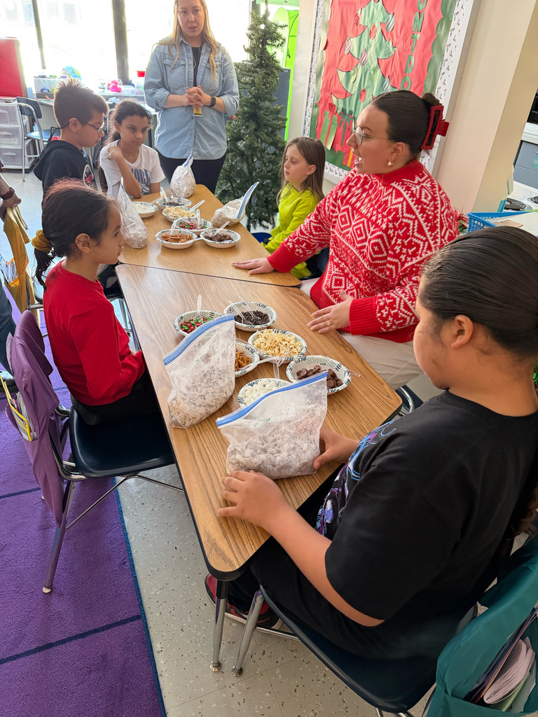 Miss O'Connor seated at table spealing with students