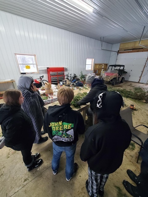 Students are shown how to make a wreath from branches. 