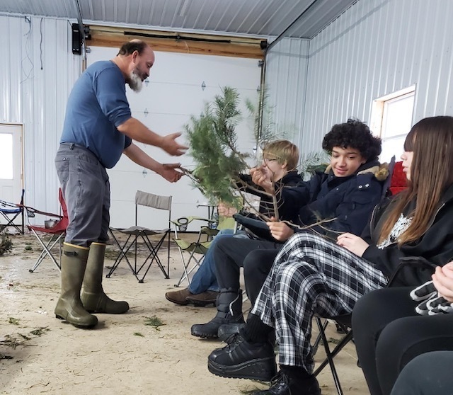 Students pass around different types of pine tree branches. 