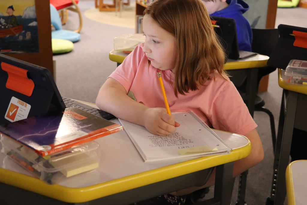 student looks at iPad while writing