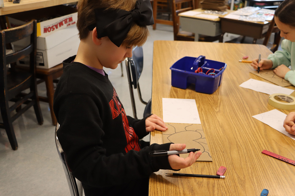 A student draws a heat design on cardboard.