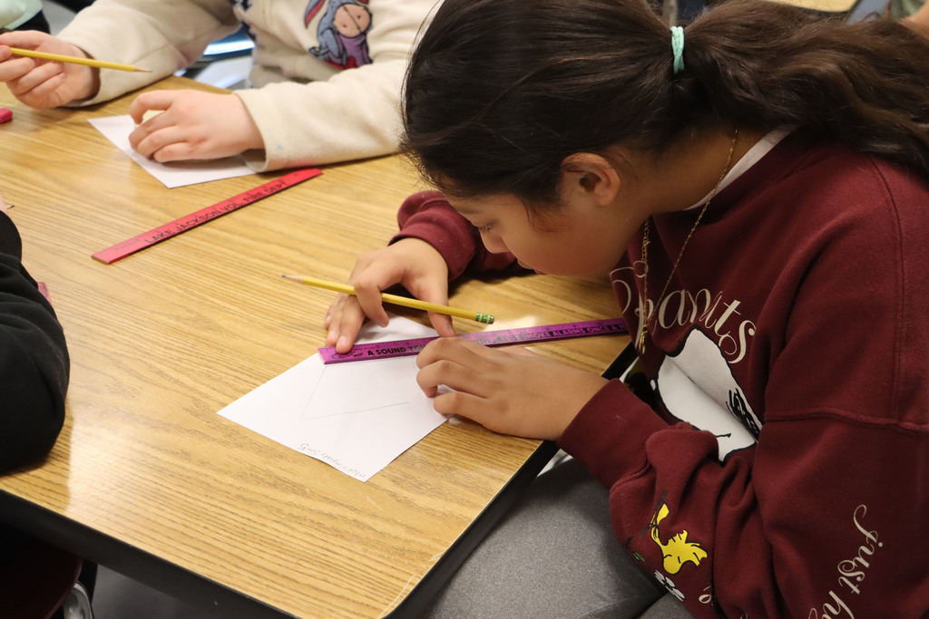 a student uses a ruler to create her design. 