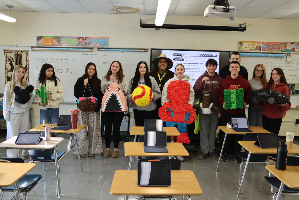 students hold up their pinatas. 
