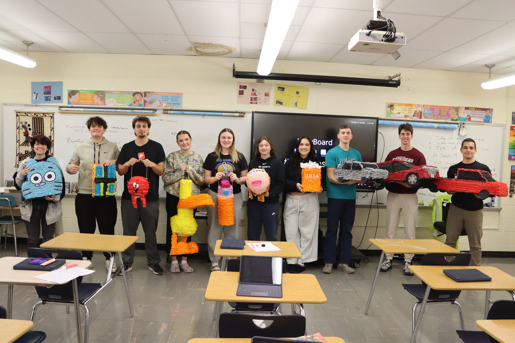 students hold up their pinatas. 