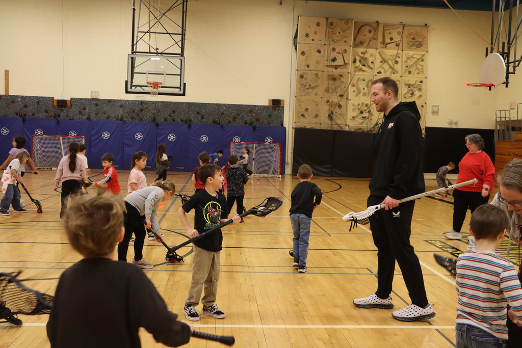 A player shows a student how to use their stick.
