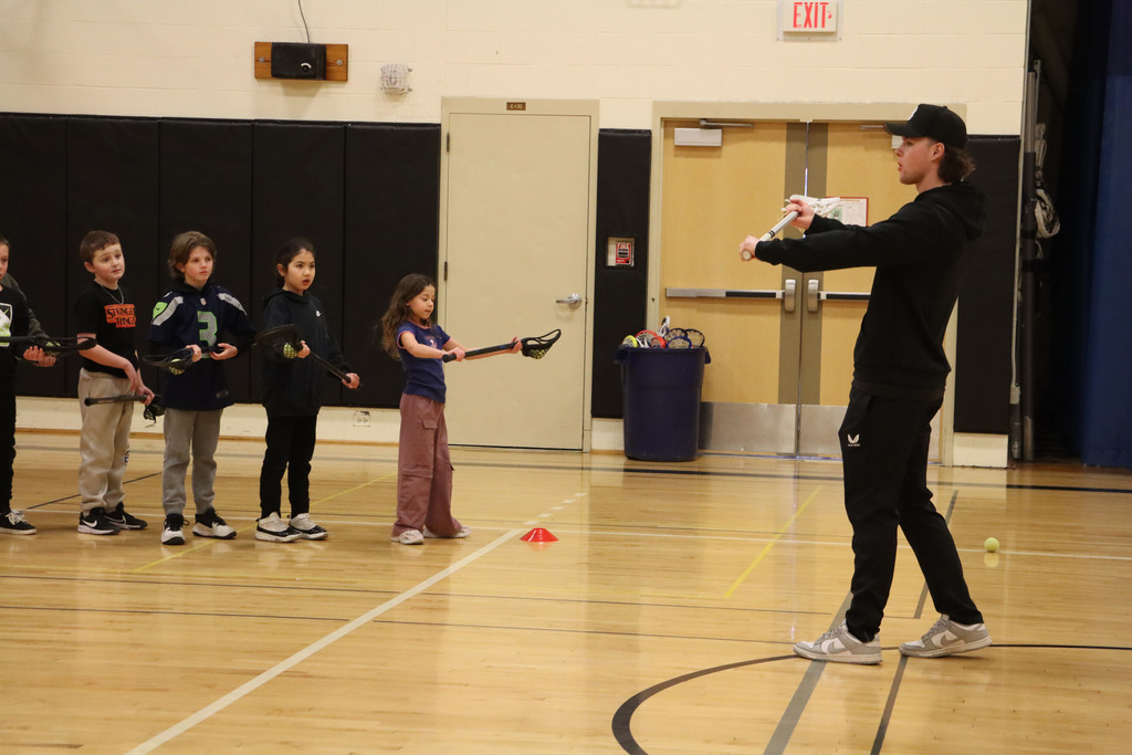 A player shows students how to use their sticks to shoot.