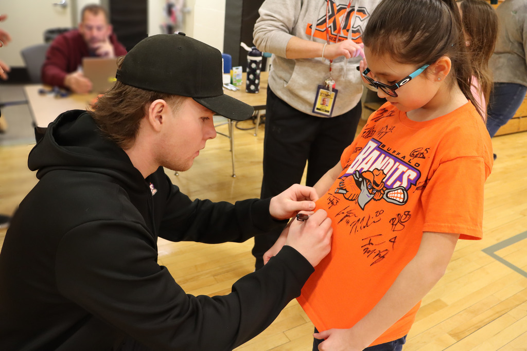 A player signs a girl's shirt. 
