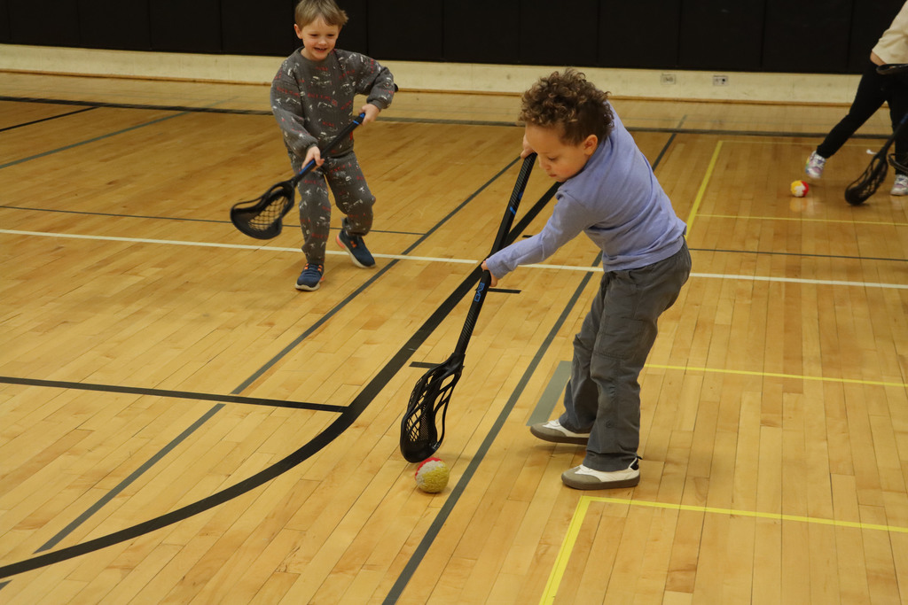 students use their sticks to pick up a ball.